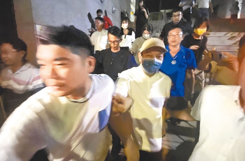 郭信良（戴帽子者）以150万新台币交保，昨晚近10点步出台南地方法院。